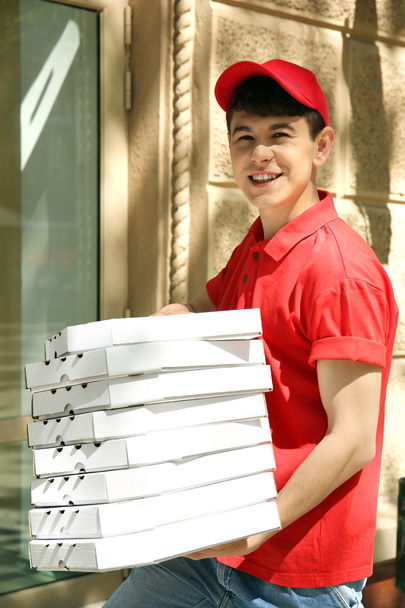 Junger Mann liefert Pizzaschachtel in Hausnähe aus - Foto, Bild