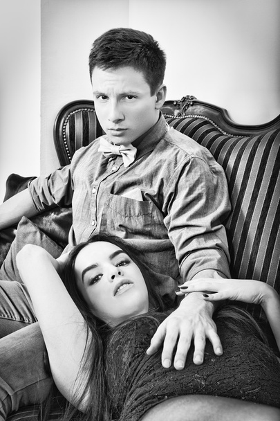 Jovem casal sentado no sofá, fotografia em preto e branco
. - Foto, Imagem