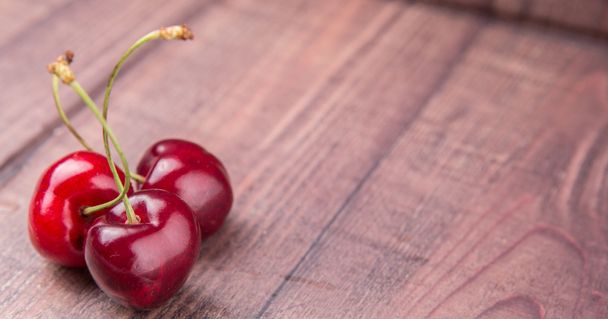 Красные плоды вишни на деревянном фоне
 - Фото, изображение