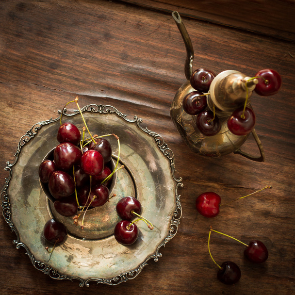 sweet cherry with a metal pitcher and dish in oriental style  - Фото, изображение