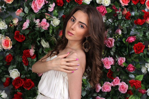 Attractive young woman in classy white dress on flower wall - Photo, Image