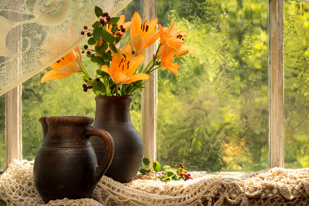 日当たりの良い雨の日の窓の土台のアジア雑種オレンジ色のユリの花束。オレンジ色の良い気分感情. - 写真・画像