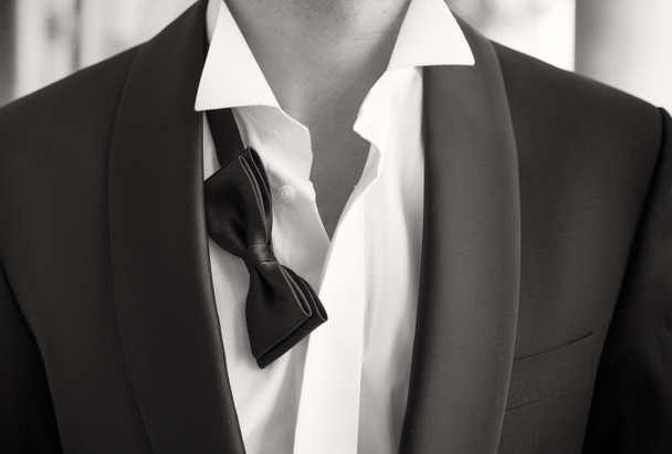 Close-up photo of man in tuxedo with open shirt and loose bow tie - Fotoğraf, Görsel