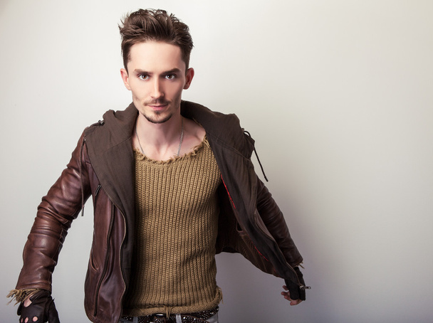 Jeune homme attrayant dans une pose de veste en cuir marron en studio
. - Photo, image