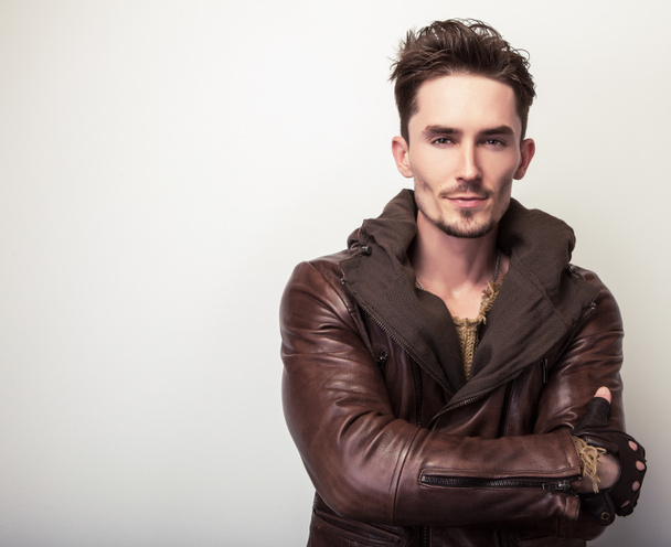 Atractivo joven en una pose chaqueta de cuero marrón en el estudio
. - Foto, imagen
