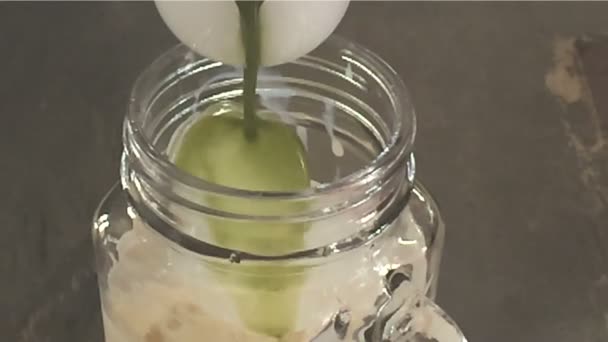 Pouring matcha green tea into milk in glass - Footage, Video