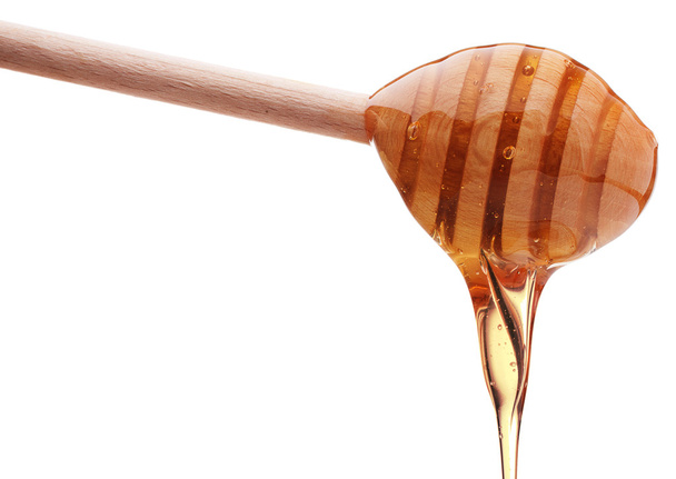 Honey dripping from wooden honey dipper - Foto, afbeelding