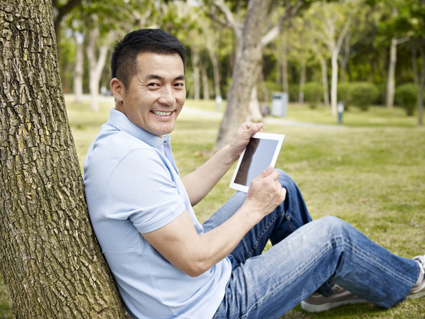 asian man using tablet outdoors - Photo, Image
