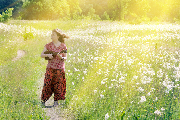 Tyttö niityllä ukulelen kanssa
 - Valokuva, kuva