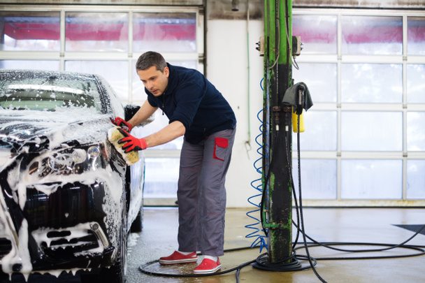 Man worker washing luxury car with sponge - Fotó, kép