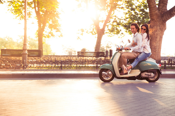 Cheerful young couple riding a scooter and having fun - Photo, Image