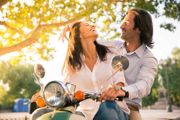 Laughing european couple flirting on scooter - Photo, image
