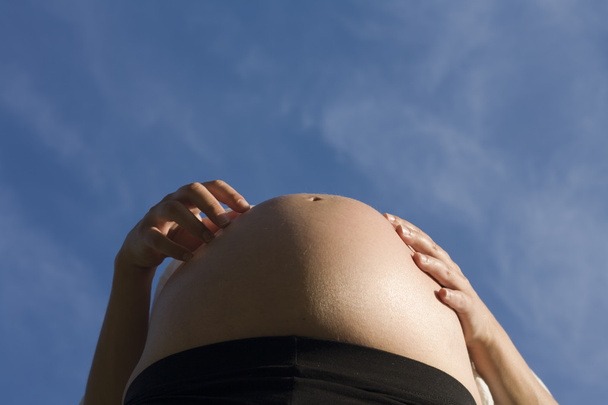 Kobieta w ciąży nad niebieski niebo - Zdjęcie, obraz