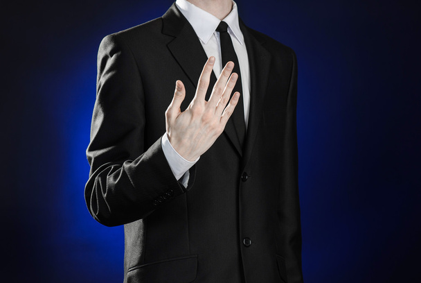 Business and the presentation of the theme: man in a black suit showing hand gestures on a dark blue background in studio isolated - Fotoğraf, Görsel