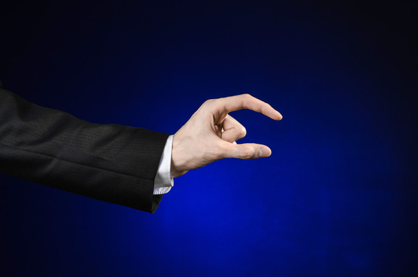 Businessman and gesture topic: a man in a black suit and white shirt showing hand gesture on an isolated dark blue background in studio - Foto, afbeelding