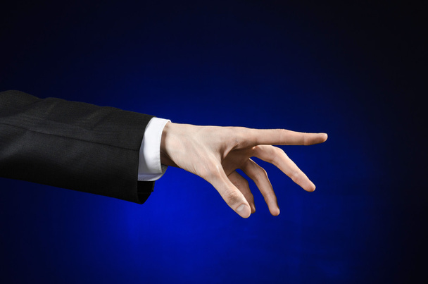 Tópico de homem de negócios e gesto: um homem de terno preto e camisa branca mostrando gesto de mão em um fundo azul escuro isolado em estúdio
 - Foto, Imagem