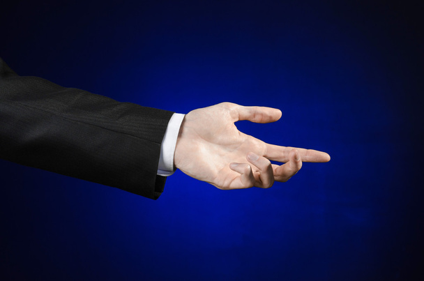 Бізнесмен і тема жесту: чоловік у чорному костюмі та білій сорочці, що показує жест рук на ізольованому темно-синьому фоні в студії
 - Фото, зображення