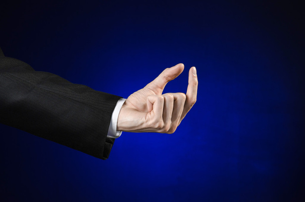Businessman and gesture topic: a man in a black suit and white shirt showing hand gesture on an isolated dark blue background in studio - Foto, Imagen