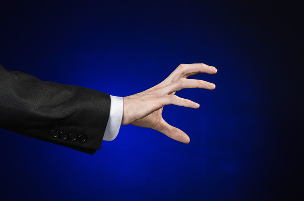 Tópico de homem de negócios e gesto: um homem de terno preto e camisa branca mostrando gesto de mão em um fundo azul escuro isolado em estúdio
 - Foto, Imagem