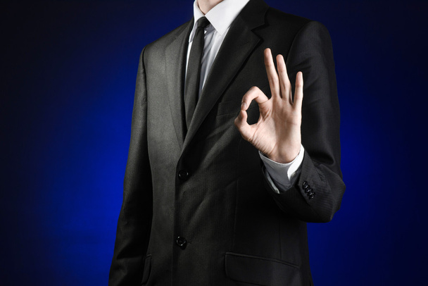 Businessman and gesture topic: a man in a black suit and white shirt showing okay hand sign on a dark blue background in studio isolated - Foto, Imagem