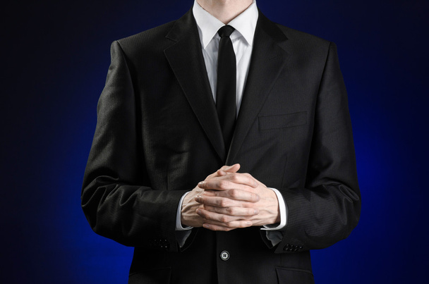 Homme d'affaires et sujet du geste : un homme en costume noir et chemise blanche tient ses mains ensemble devant vous et prie, médite sur un fond bleu foncé dans un studio isolé
 - Photo, image