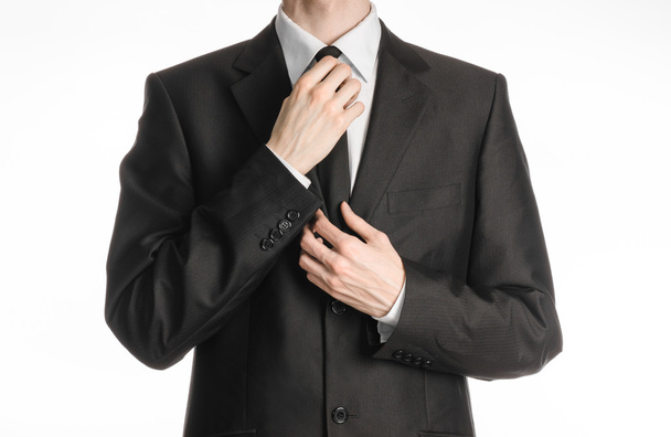 Businessman and gesture topic: a man in a black suit with a tie straightens his tie isolated on white background in studio - Photo, image