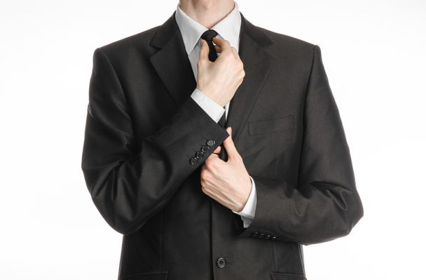Hombre de negocios y tema de gestos: un hombre de traje negro con corbata endereza su corbata aislada sobre fondo blanco en el estudio
 - Foto, imagen