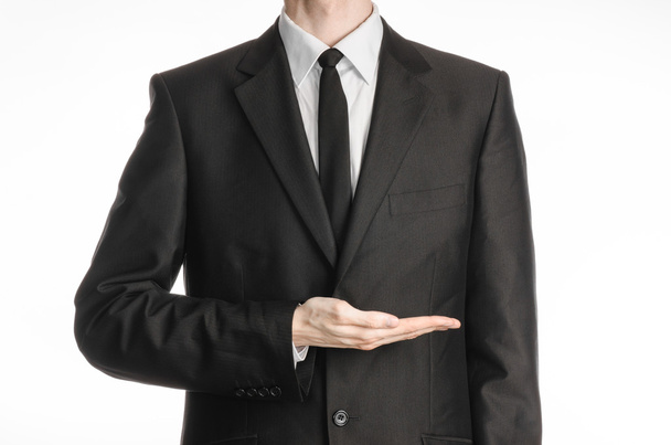 Businessman and gesture topic: a man in a black suit and tie holding his hand in front of him isolated on a white background in studio - Foto, Bild