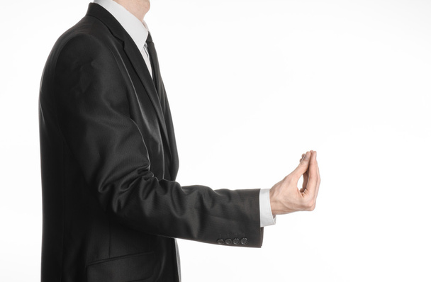 Businessman and gesture topic: a man in a black suit and tie holding his hand in front of him and shows a pinch gesture on an isolated white background in studio - Foto, afbeelding