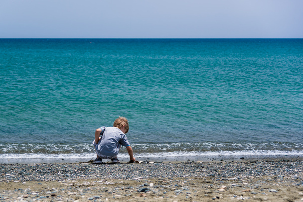 Boy playing with stones on a beach  - Foto, afbeelding