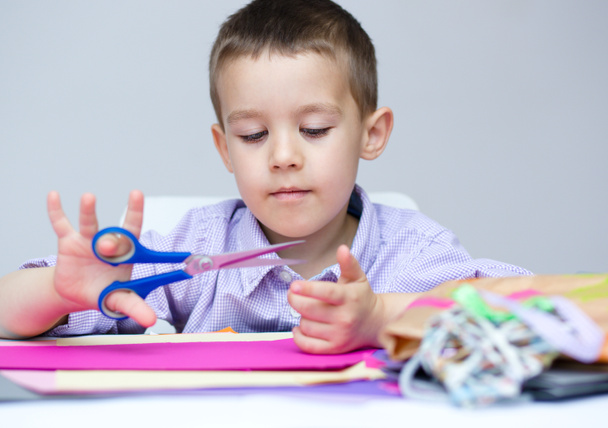 Boy is cutting paper using scissors - Photo, Image