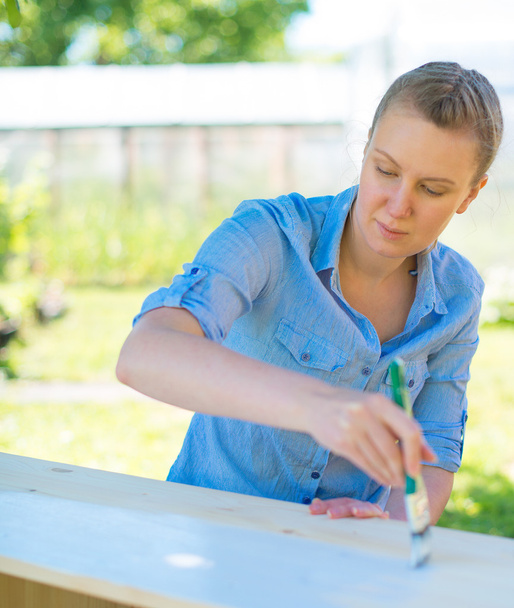Mujer con pincel pintando muebles de madera
. - Foto, imagen