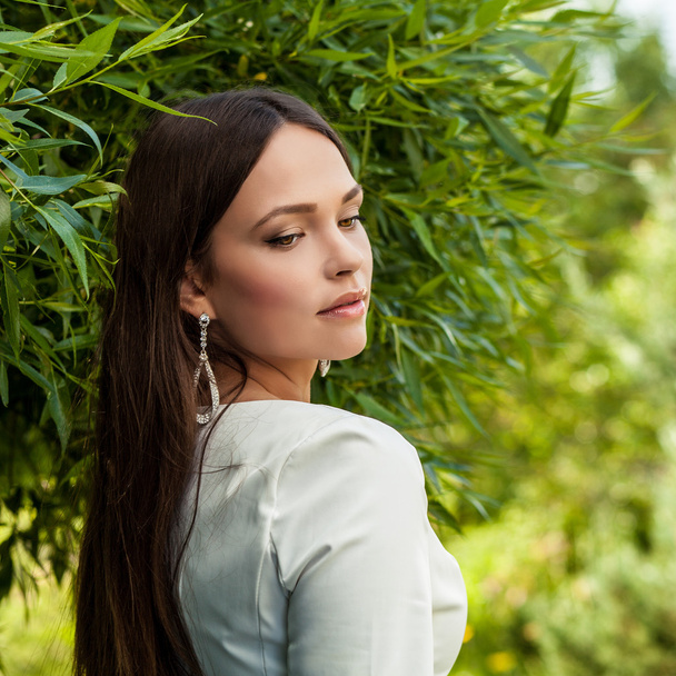 Outdoors portrait of beautiful young girl in luxury white dress posing in summer garden. - Φωτογραφία, εικόνα