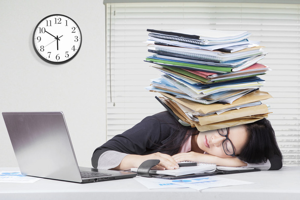 Woman sleeping in office with paperwork on head - Zdjęcie, obraz