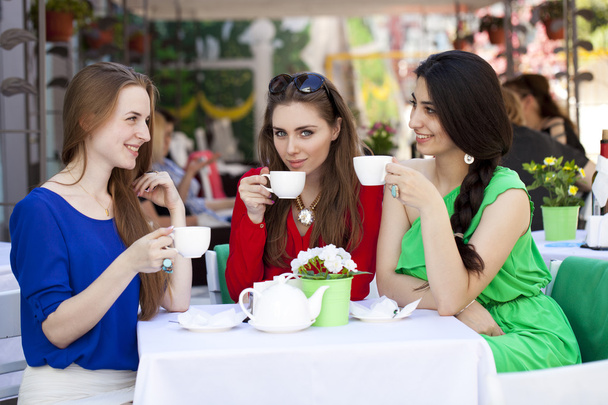 Three happy girlfriends woman sitting at a table in the summer c - Photo, Image