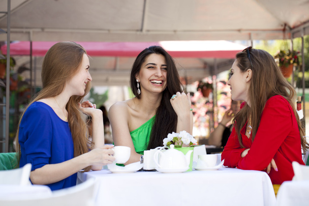 Three happy girlfriends woman sitting at a table in the summer c - Foto, Bild