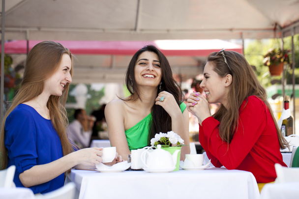 Three happy girlfriends woman sitting at a table in the summer c - Фото, изображение