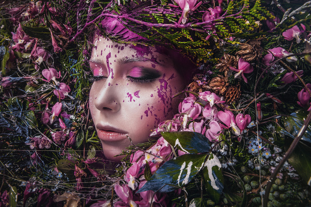 Fairy tale girl portrait surrounded with natural plants and flowers. Art image in bright fantasy stylization. - Фото, изображение