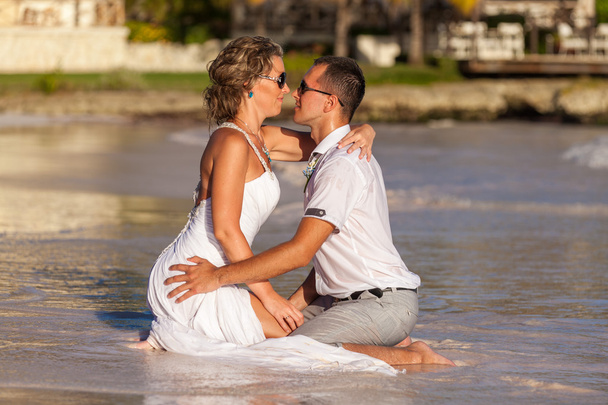 Young couple sitting together on a sand by ocean - Foto, Imagen