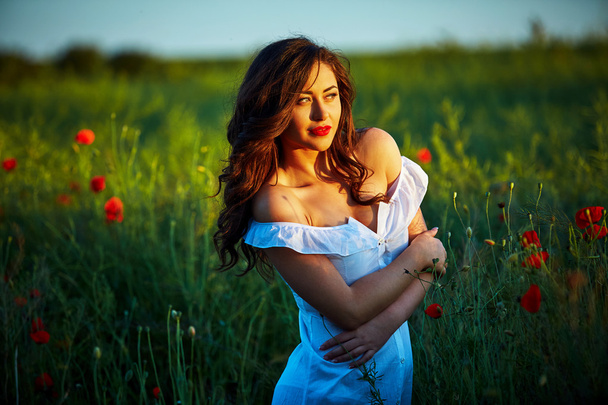 Beautiful woman in a poppy field with flowers - Photo, Image