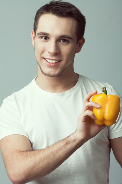 Raw, living food concept. Portrait of young man with sweet pepper - Photo, Image