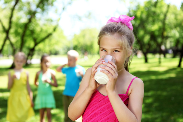 Girl drinking milk in the summer park - Photo, Image