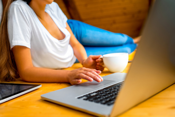 Женщина, работающая с ноутбуком на деревянном полу
 - Фото, изображение