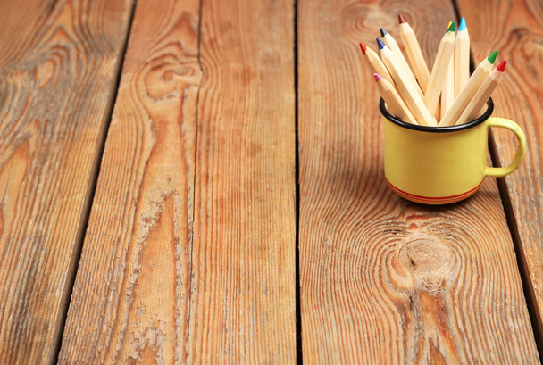 Олівці в чашці на дерев'яному столі
 - Фото, зображення