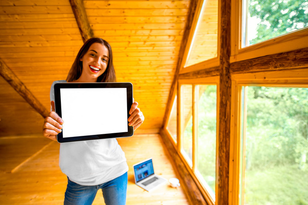 Женщина показывает цифровой планшет в деревянном доме
 - Фото, изображение