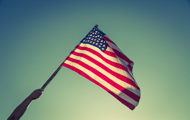 Americká vlajka s hvězdami a pruhy držet rukou proti blu - Fotografie, Obrázek