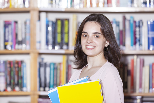 Female student holding books at the library - Foto, afbeelding