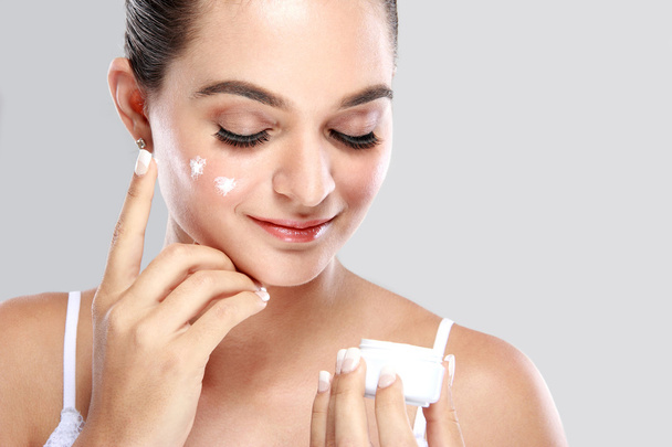 beautiful woman applying some cream to her face - Foto, afbeelding