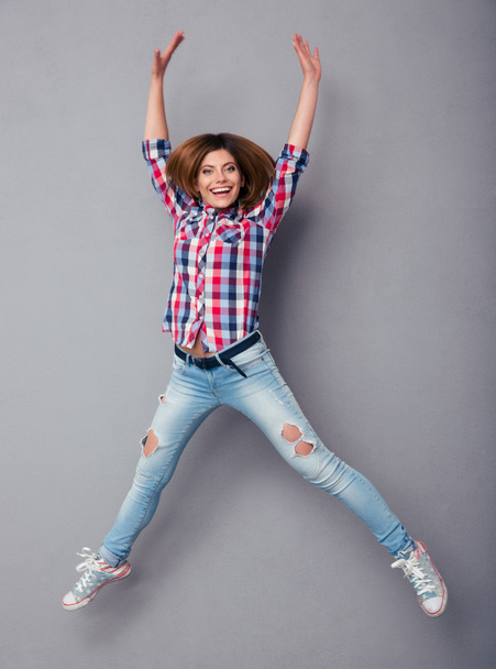 Smiling young woman jumping isolated on gray - Fotoğraf, Görsel