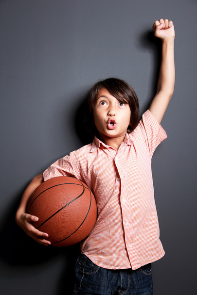 alegre niño levantó la mano y sosteniendo una pelota de baloncesto
 - Foto, Imagen